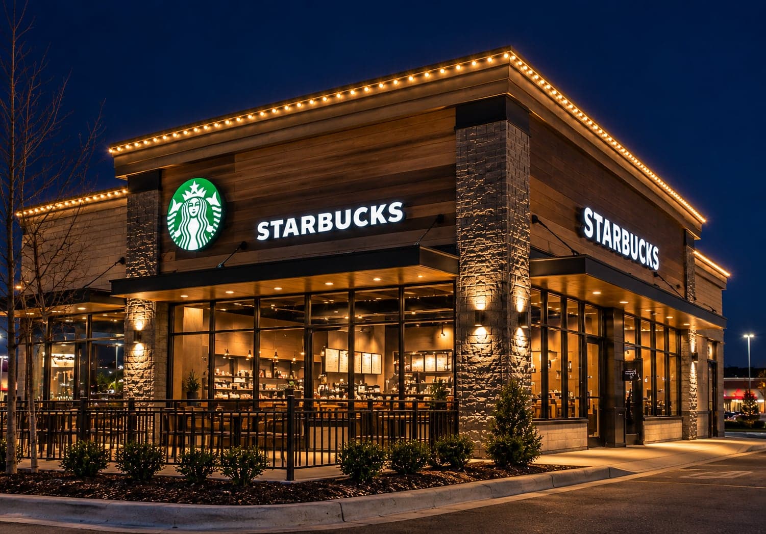 Coffee shop at night with warm-white lighting along the roofline, stone pillars and covered patio